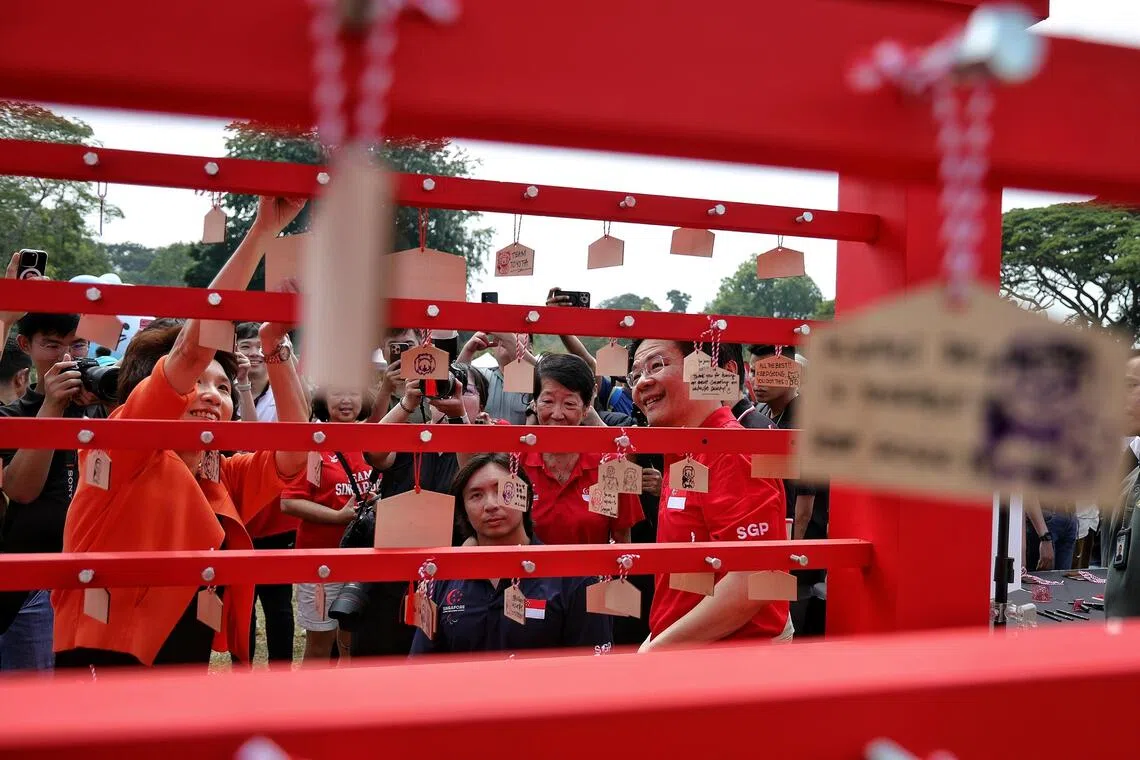 (From right) Prime Minister Lawrence Wong, Singapore National Paralympic Council (SNPC) president Teo-Koh Sock Miang, para-swimmer Toh Wei Soong and South West District mayor Low Yen Ling hanging their penned well wishes for Team Singapore at the launch of the inaugural Paralympic Day, at Angsana Green, East Coast Park, on Aug 29.