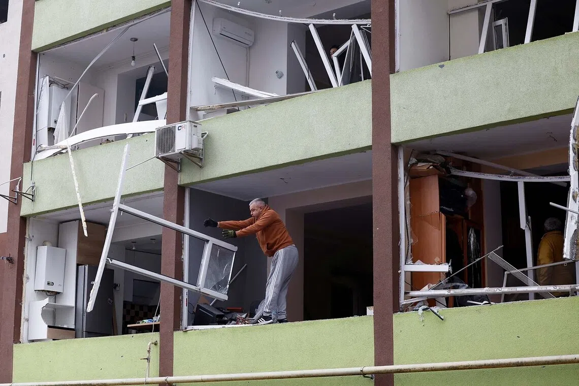 A man removing debris from a damaged building in a residential neighbourhood after overnight Russian drone and missile attacks in Kyiv, Ukraine, Sept 28, 2025. 