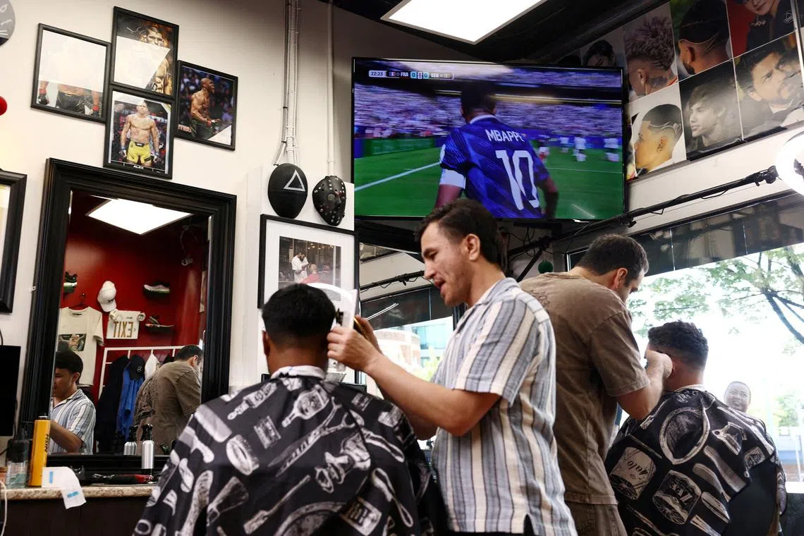 Customers having their hair cut at a barber shop as the FIFA World Cup 2026 match between France and Senegal, is shown on the television, in Vancouver, Canada, on  June 16, 2026.