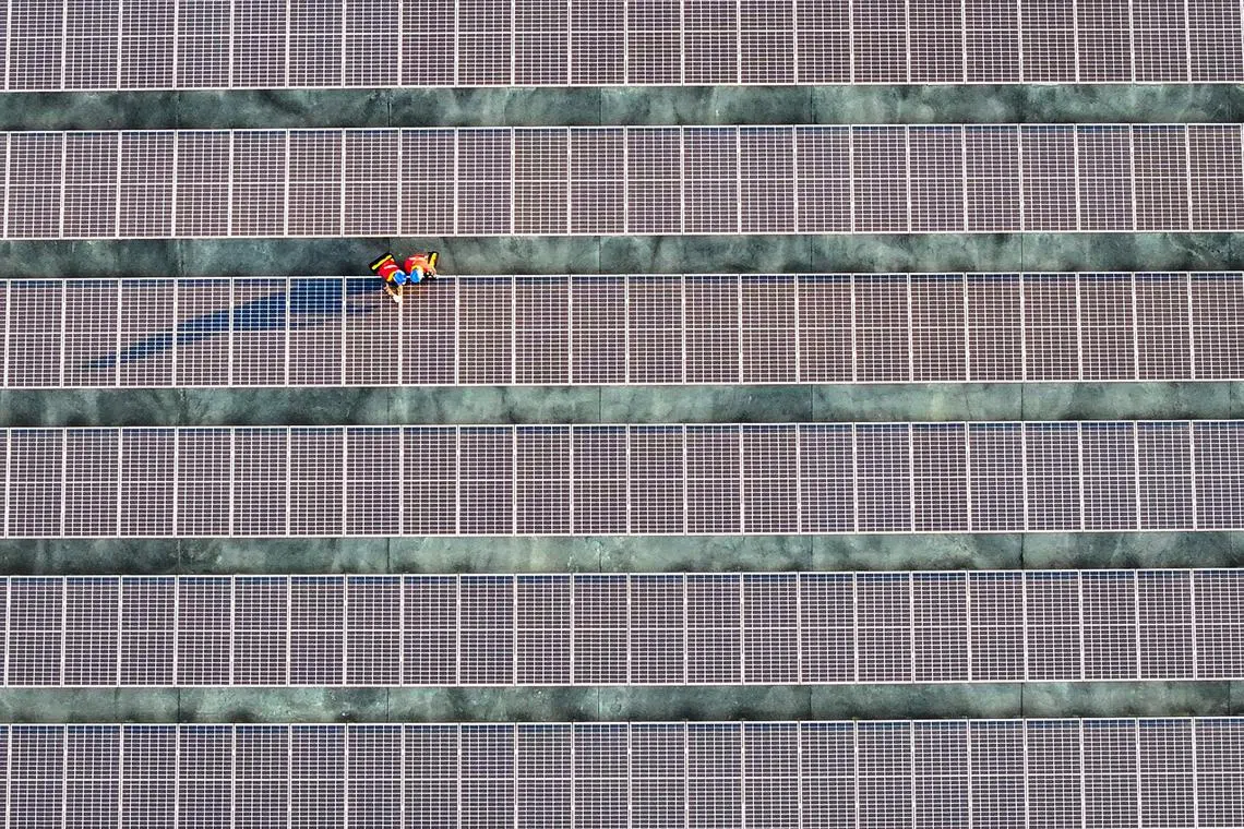 This photo taken on February 21, 2024 shows workers inspecting solar panels at a rooftop of a power plant in Fuzhou, in southern China's Fujian province. (Photo by AFP) / China OUT