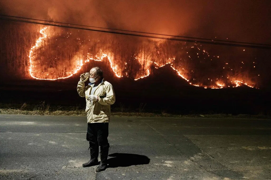 A man talks to his son on the phone in front of his home as wildfires burn in Uiseong, South Korea, on March 24, 2025. 