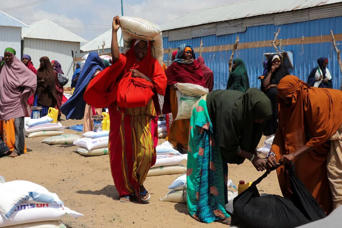FILE PHOTO: Internally displaced Somali women carry their relief packages after receiving dry relief food from Kuwait charity, during the Muslim holy fasting month of Ramadan, in Mogadishu, Somalia March 12, 2025. REUTERS/Feisal Omar/File Photo