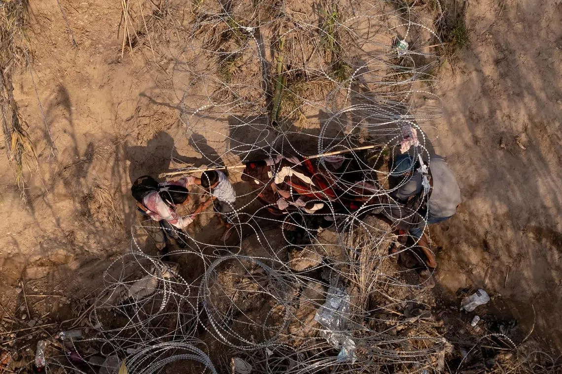 A migrant child crawls out through concertina wire along the banks of the Rio Grande River while crossing from Mexico into Eagle Pass, Texas, U.S., December 19, 2023. REUTERS/Cheney Orr TPX IMAGES OF THE DAY