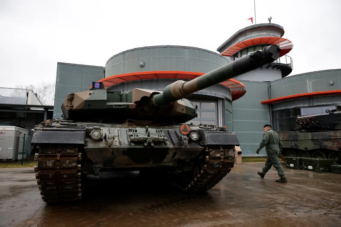 Polish soldiers walks by a Leopard 2PL tank in Swietoszow, Poland, on Jan 31, 2023.