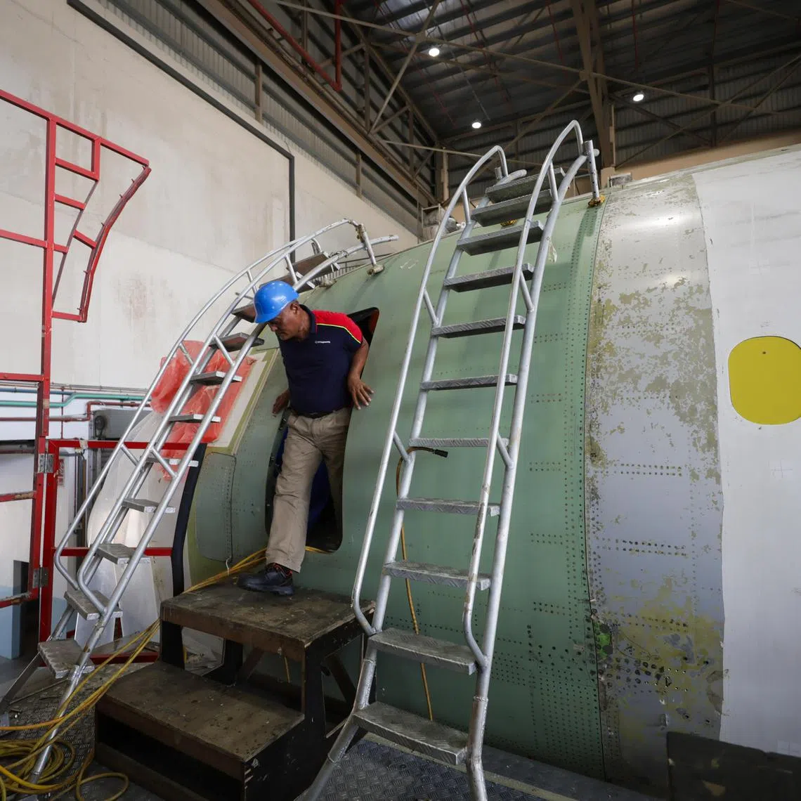 ST20240207_202454992664: Gin Tay/ mystengg07/ Mike Yeo/
Mr M Razali Bin Ahmad, 62, a Project Manager at ST Engineering, exits the crew door of an Airbus A321 being converted into a freighter at Seletar Aerospace Park. The original front boarding door or the passenger aircraft is replaced with a smaller door located further forward, to enable more cargo to be carried. 
(photographed on Feb 7, 2024)