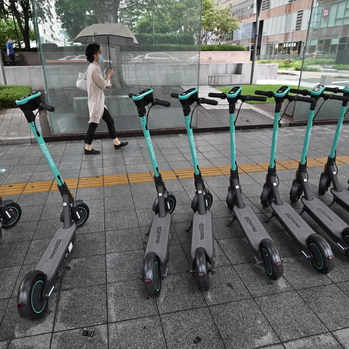A woman walks past electric kickboards parked on a street in central Seoul on July 23, 2020. South Korea's economy recorded its worst performance in more than 20 years in the second quarter, the central bank said on July 23, as the coronavirus pandemic hammered its exports. (Photo by Jung Yeon-je / AFP)