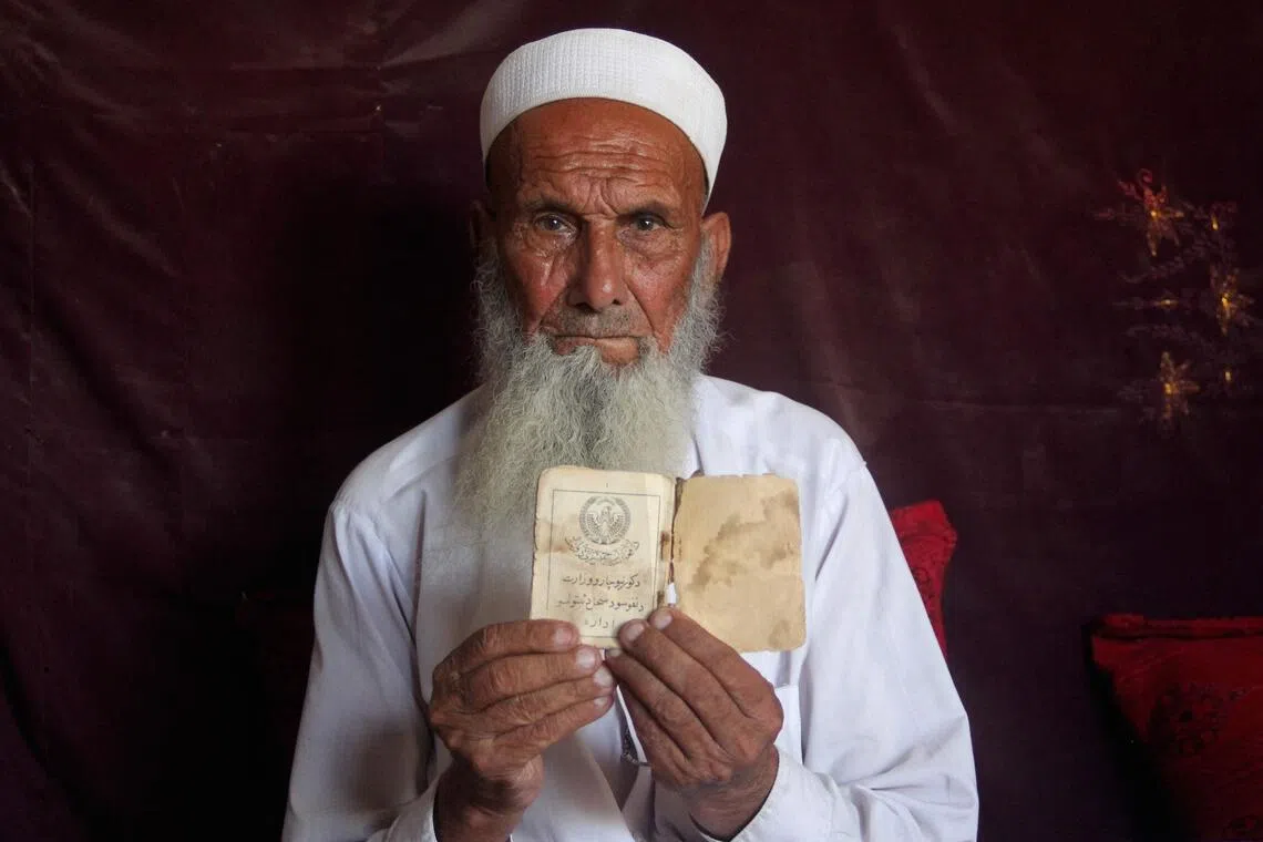 Murat Khan Safi, an Afghan returnee deported from Pakistan, holding his old Afghan identity card inside a rented house at Afghanistan’s Nangarhar province.