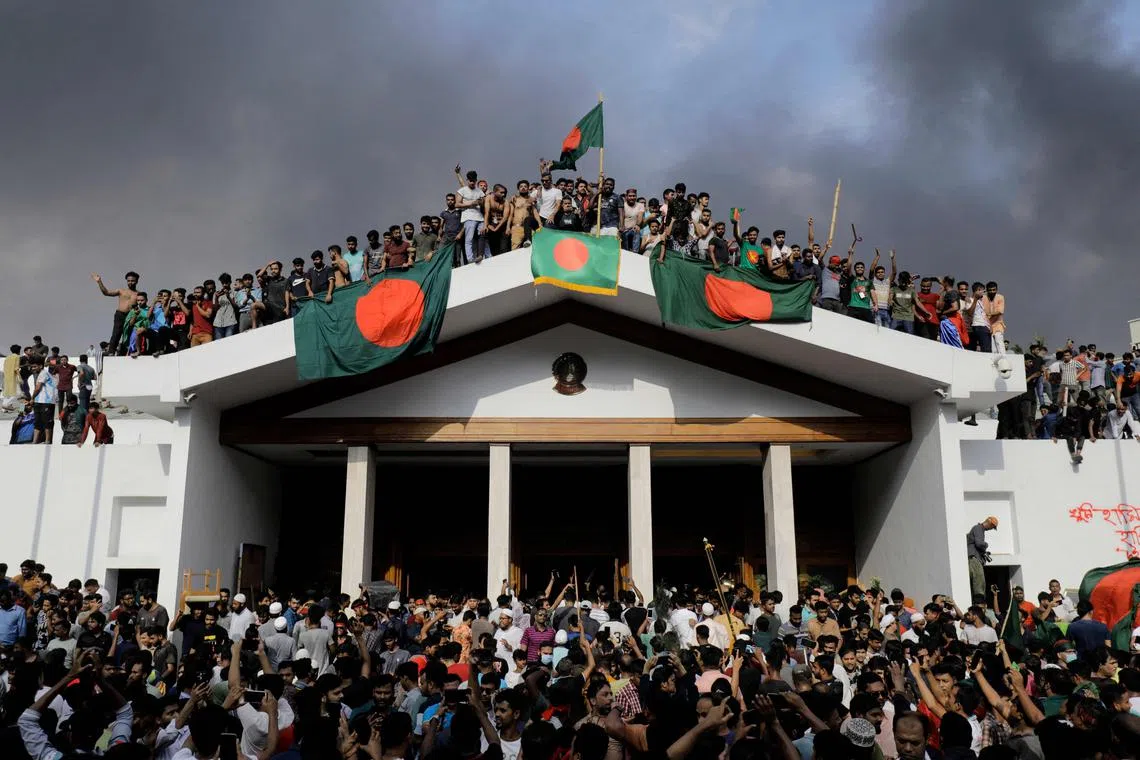 Anti-government protestors display Bangladesh's national flag as they storm Prime Minister Sheikh Hasina's palace in Dhaka on Aug 5.