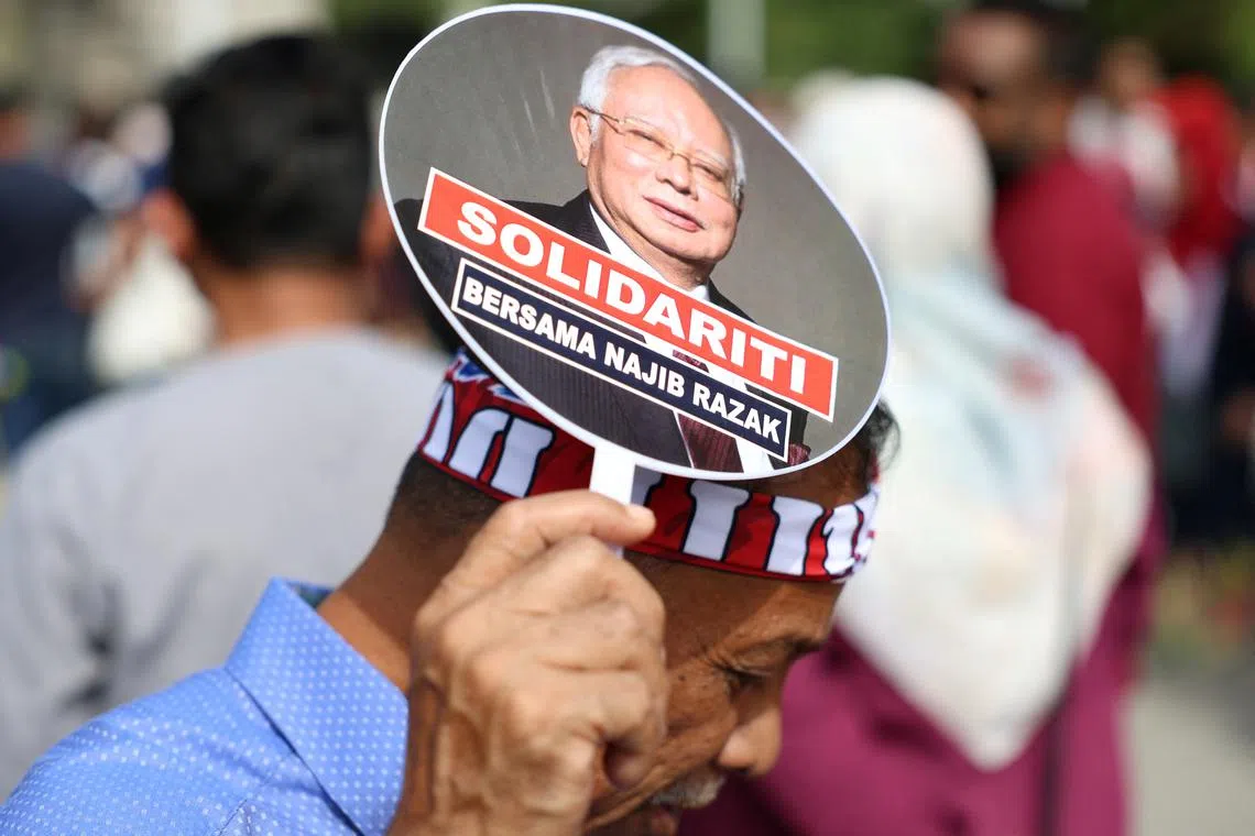 FILE PHOTO: A supporter of former Malaysian Prime Minister Najib Razak holds a hand fan bearing his image outside the Court of Appeal, where his case is being heard in Putrajaya, Malaysia, January 6, 2025. REUTERS/Hasnoor Hussain/File Photo