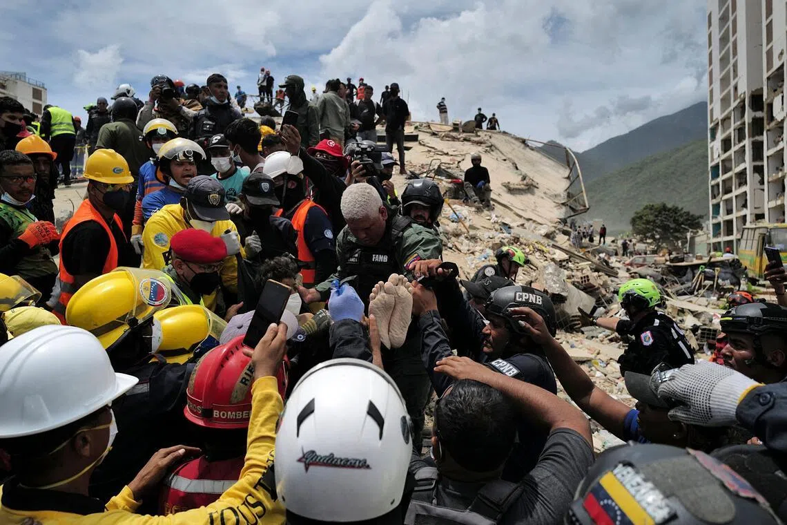 Rescuers carry a person after being pulled alive from the rubble of a collapsed building in Caraballeda, La Guaira state, Venezuela, on June 28.