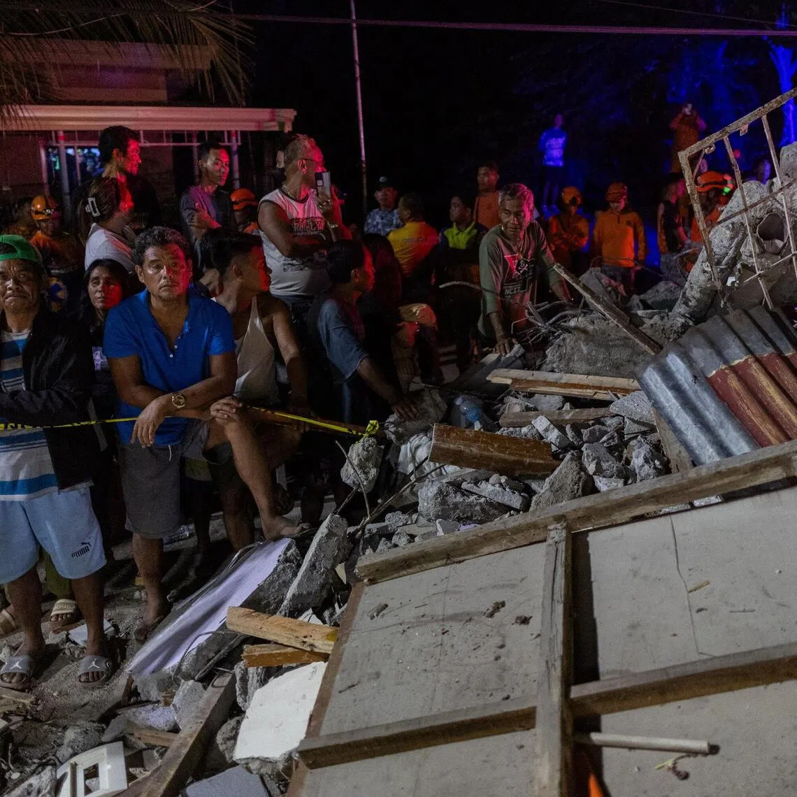 Residents watch as rescuers retrieve bodies of victims found under the rubble of a damaged pension house in the aftermath of a magnitude 6.9 quake in Bogo, Cebu, Philippines, October 1, 2025. REUTERS/Eloisa Lopez