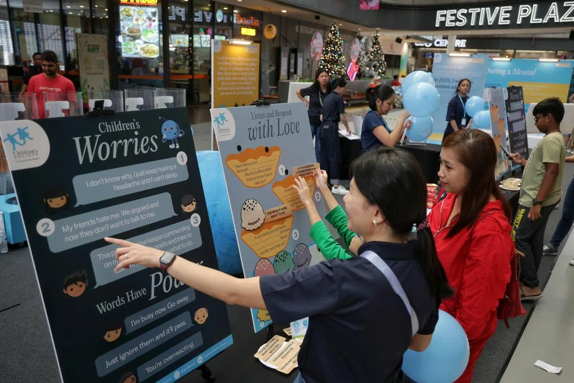A staff (in dark blue polo tee)from Children's Society guiding members of the public on how to listen to children's worries and respond with love at an activity booth during Tinkle Friend's (Singapore's only toll-free helpline for primary school children) 40th anniversary event at Our Tampines Hub on Dec 21, 2024.