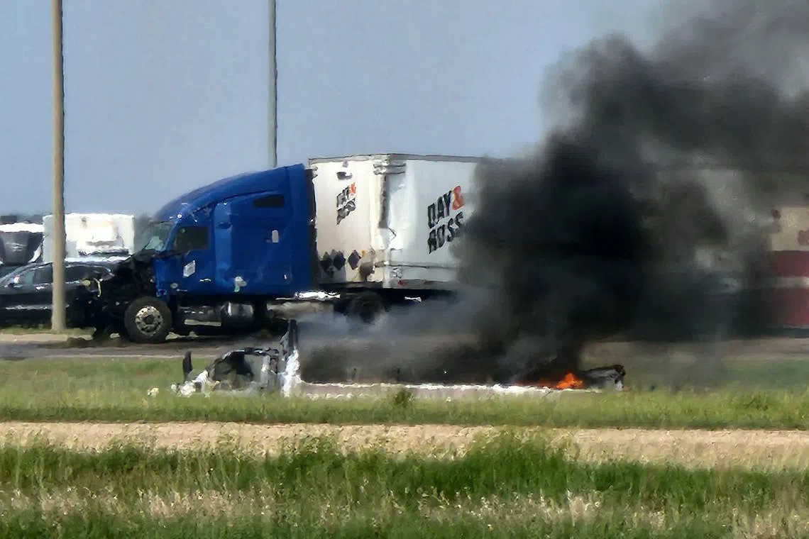 Smoke rises from a car following the road accident near Carberry, west of Winnipeg.