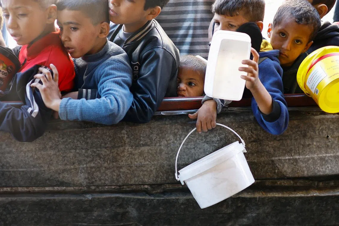 Palestinian children wait to receive food cooked by a charity kitchen amid shortages of food supplies, amid the ongoing conflict between Israel and the Palestinian Islamist group Hamas, in Rafah in the southern Gaza Strip, January 16, 2024. REUTERS/Ibraheem Abu Mustafa/File Photo