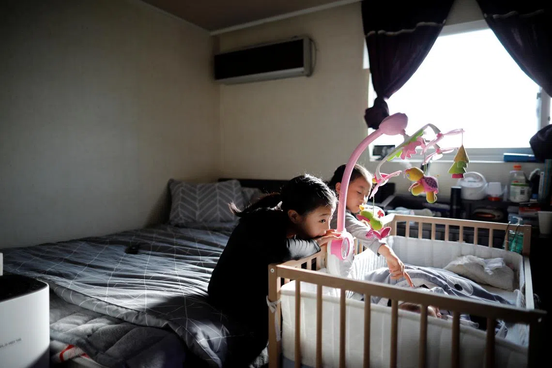 FILE PHOTO: Girls take care of their baby brother before leaving for school, at their home in Seoul, South Korea, December 19, 2018. REUTERS/Kim Hong-Ji/File photo
