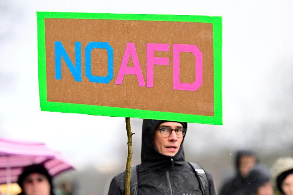 FILE PHOTO: A protester holds a sign in the rain, at a demonstration against the Alternative for Germany (AfD) party, right-wing extremism and for the protection of democracy in Hamburg, Germany, February 25, 2024. REUTERS/Fabian Bimmer/File Photo