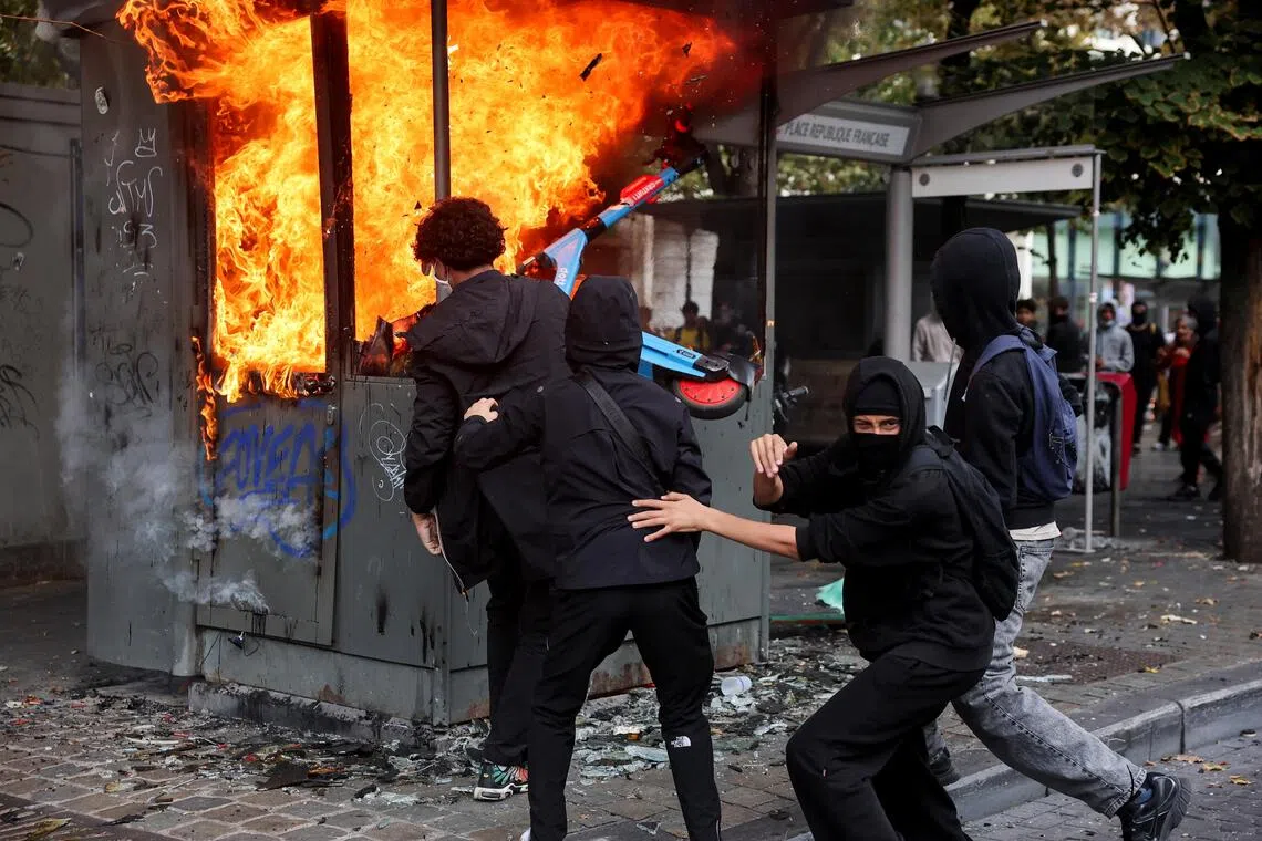 Protesters in Liege on Oct 7, attempting to put an electric scooter into a burning structure. Hundreds of students took to the streets, with Belgian media reporting 107 arrests relating to property damage and arson.