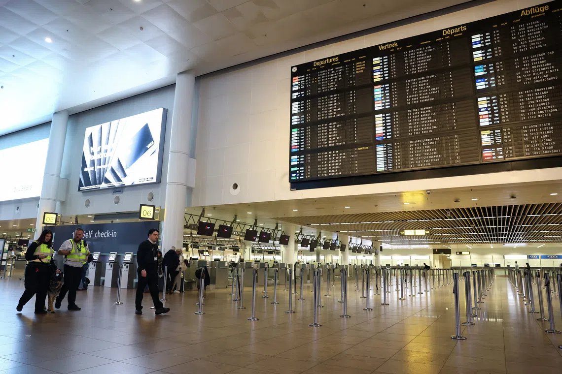 Staff walk past a departures board at Brussels Airport after the Belgian air traffic control service reported a sighting of a drone, in Zaventem, Belgium, November 4, 2025. REUTERS/Yves Herman