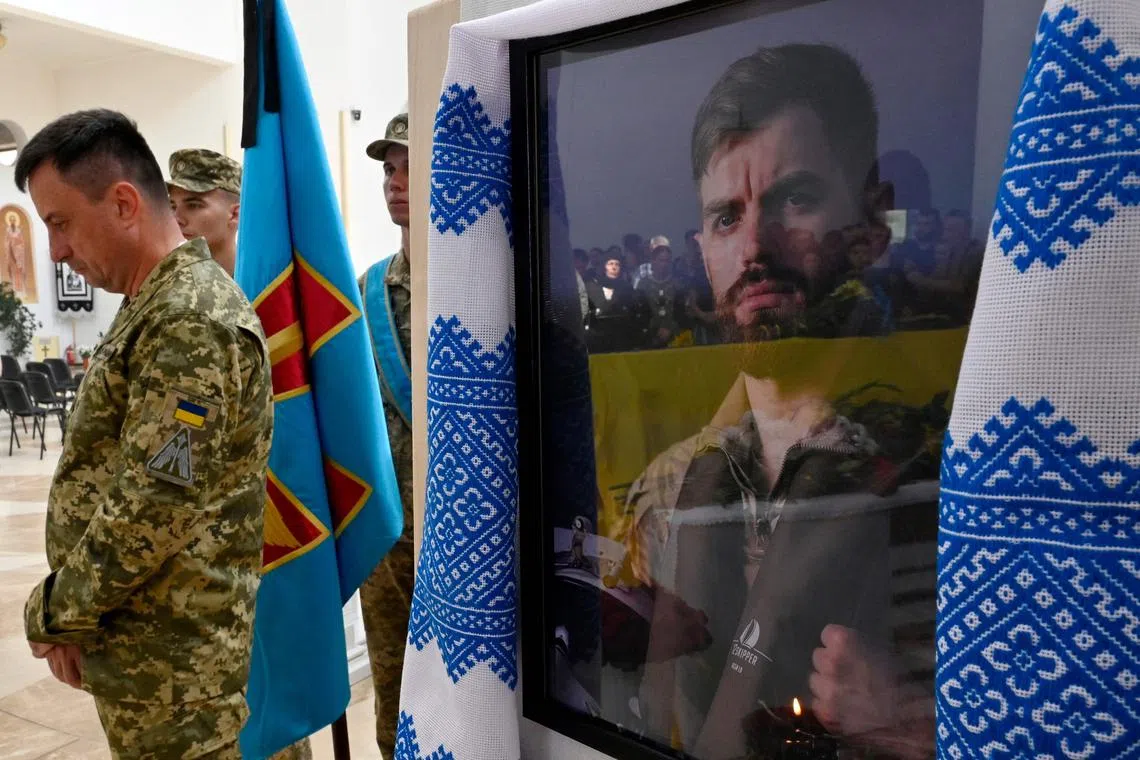 Relatives and friends of Ukrainian pilot Andriy Pilshchykov are reflected in his portait during a funeral ceremony in Kyiv.
