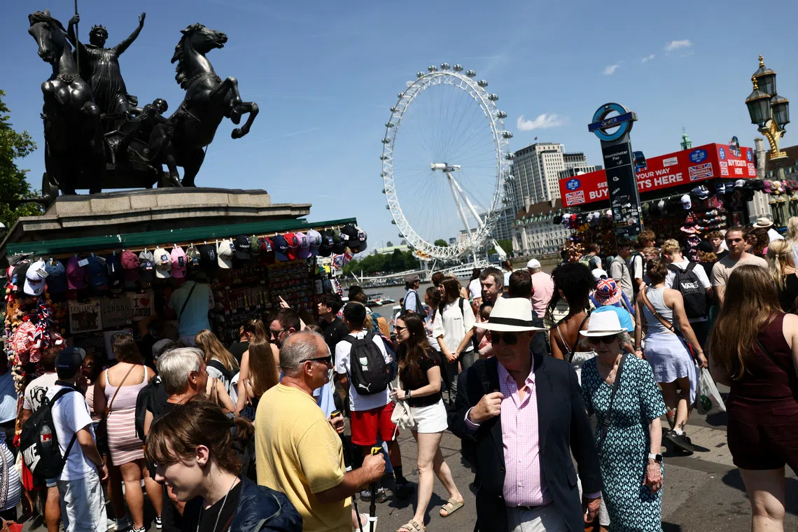 A crowd gathers around a large bronze equestrian statue with a Ferris wheel visible behind it.