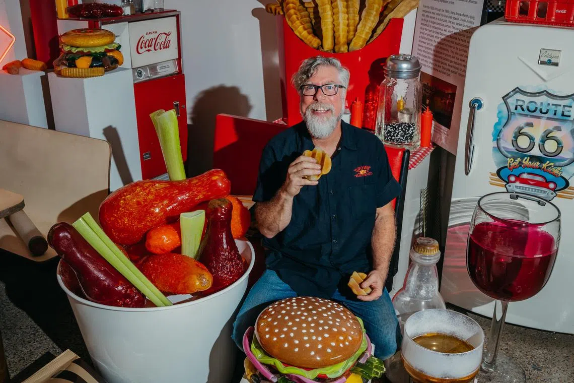 Artist John Miller amidst his whimsical, oversized glass food sculptures at his studio in Bloomington. 