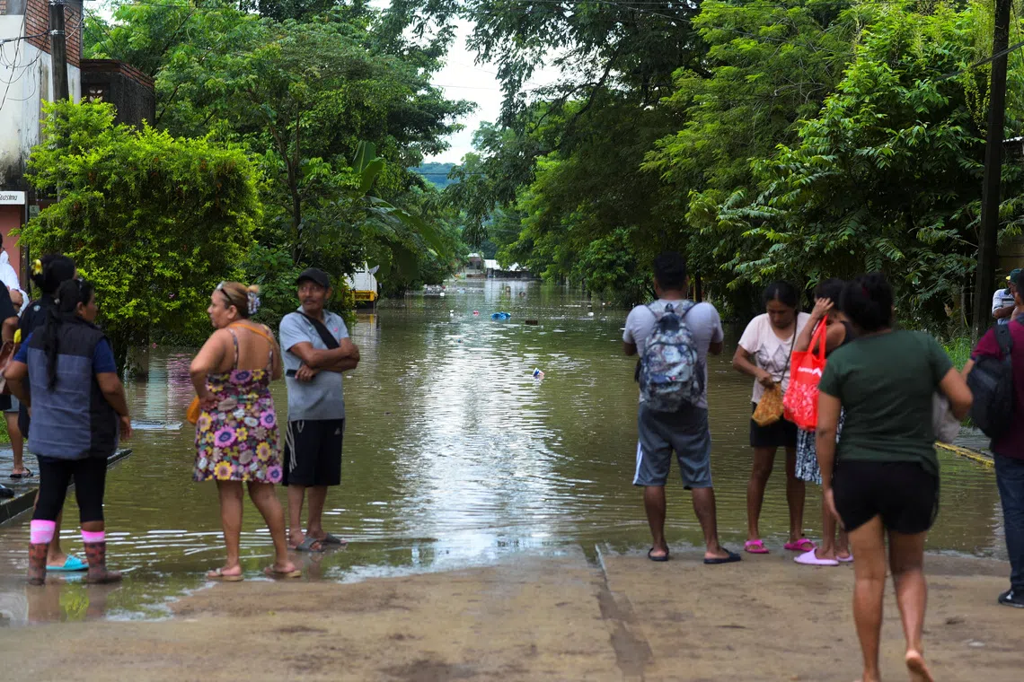People look at a flooded street after torrential rains that caused an overflow of rivers in Poza Rica, Veracruz state, Mexico, October 10, 2025. REUTERS/Rolando Ramos