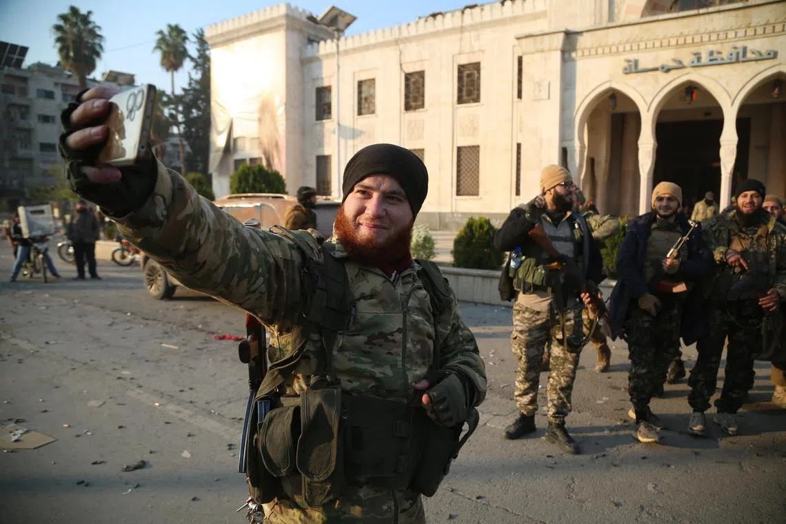 Rebel fighters posing for a selfie in front of a Syrian government building, after they entered the city of Hama, on Dec 6.