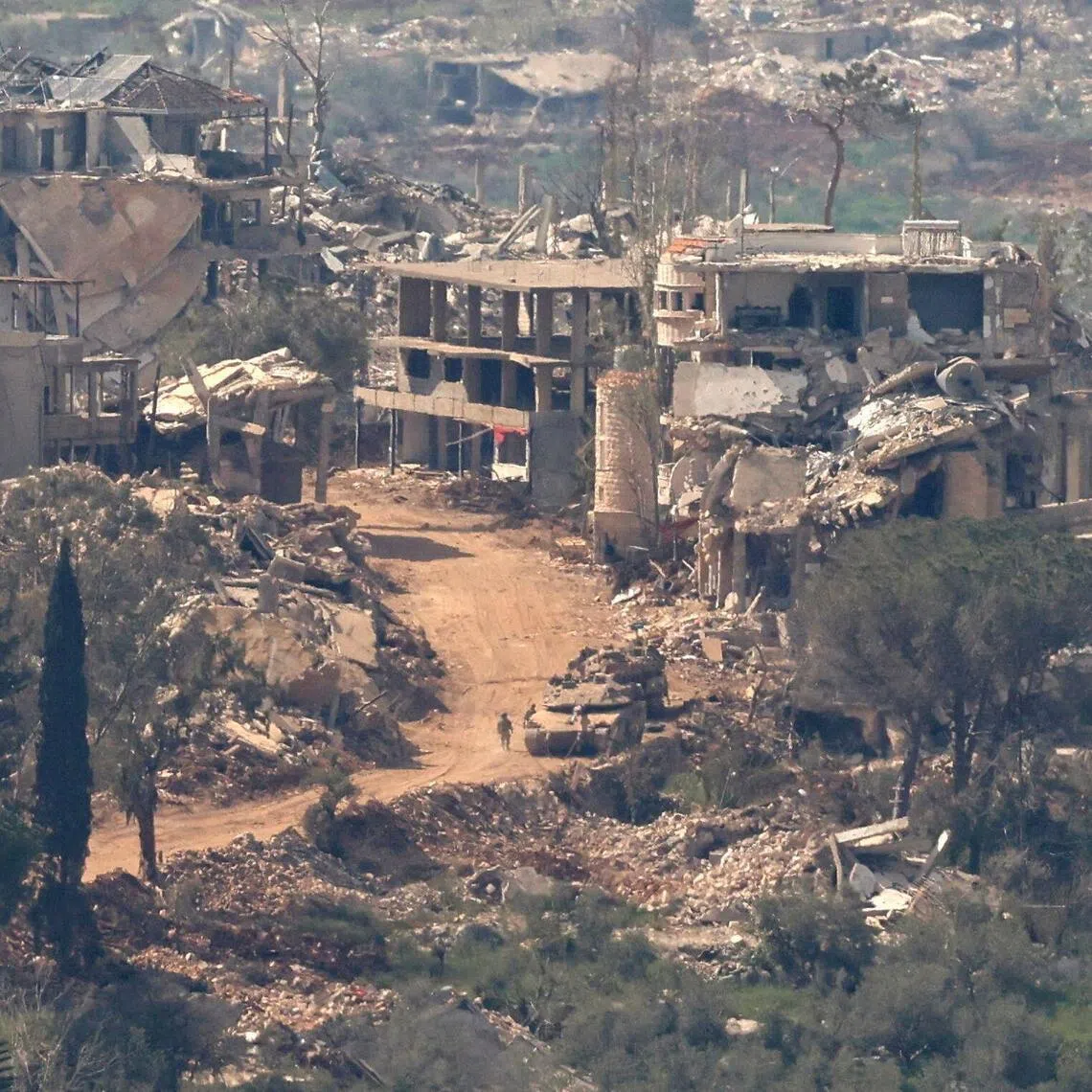 Israeli tanks and military vehicles driving along a road between destroyed houses in southern Lebanon, near the border with Israel, on April 25.