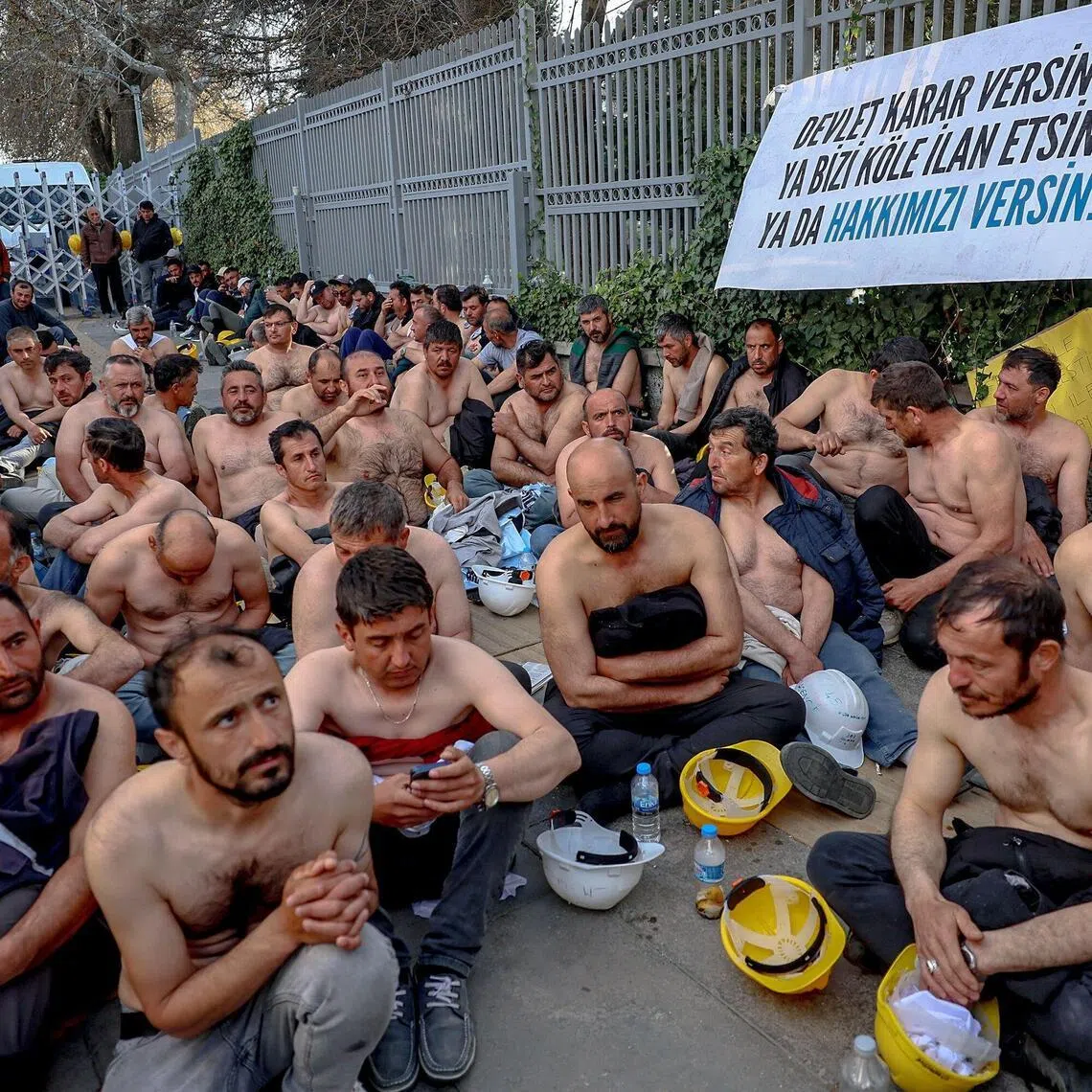 Around 90 miners stage topless a sit-in protest outside Turkey's Energy Ministry, with a banner hanged on its fence reading "Let the goverment decide: Either declare us slaves, or grant us our rights", to demand unpaid wages in Ankara, on April 20, 2026. Hundreds of workers from Doruk Mining, members of the Independent Miners' Union, walked a 180-kilometre way in nine days to reach Ankara, calling on authorities to address what they described as months of delayed payments and unresolved compensation claims. (Photo by Adem ALTAN / AFP)
