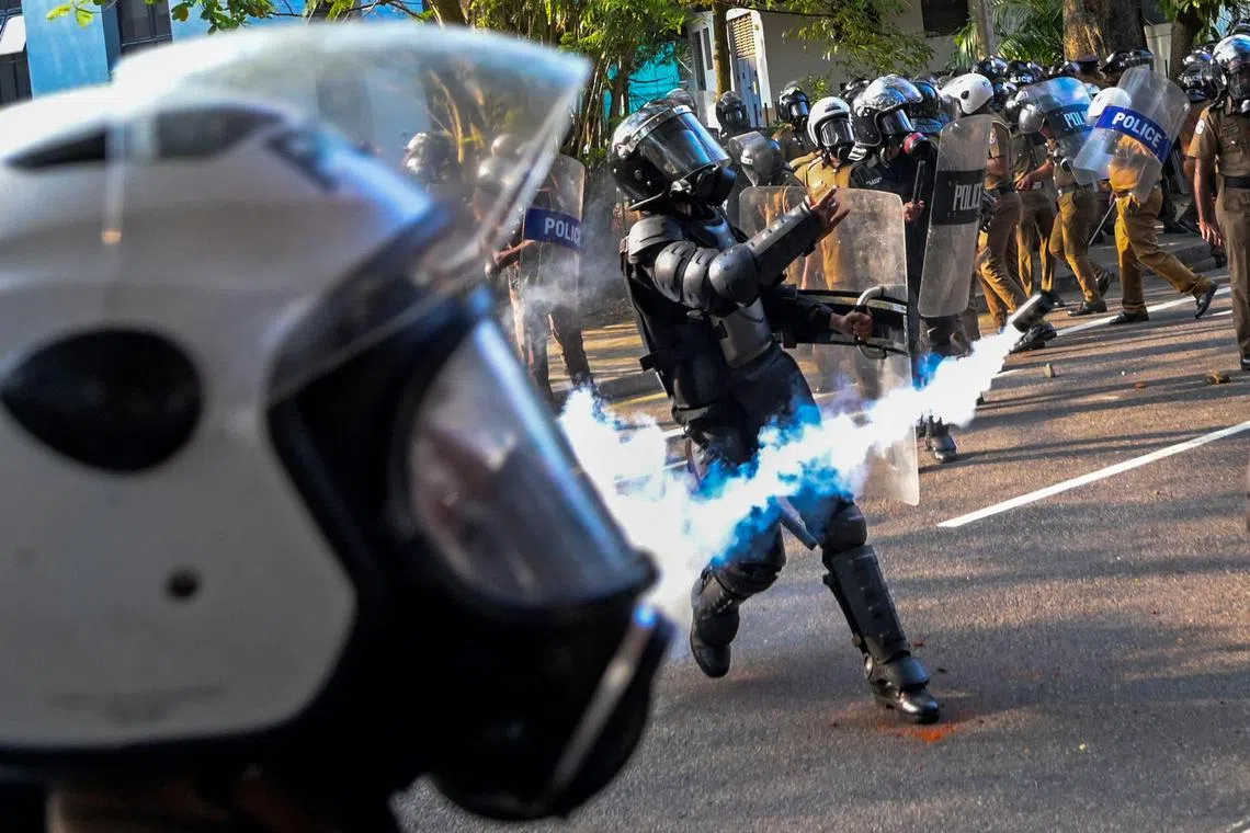 Policeman throws a tear gas to disperse anti-government demonstrators and university students during a protest demanding the release of Inter University Students' Federation leaders and urging the government to hold local council election as scheduled, in Colombo on March 7, 2023. 