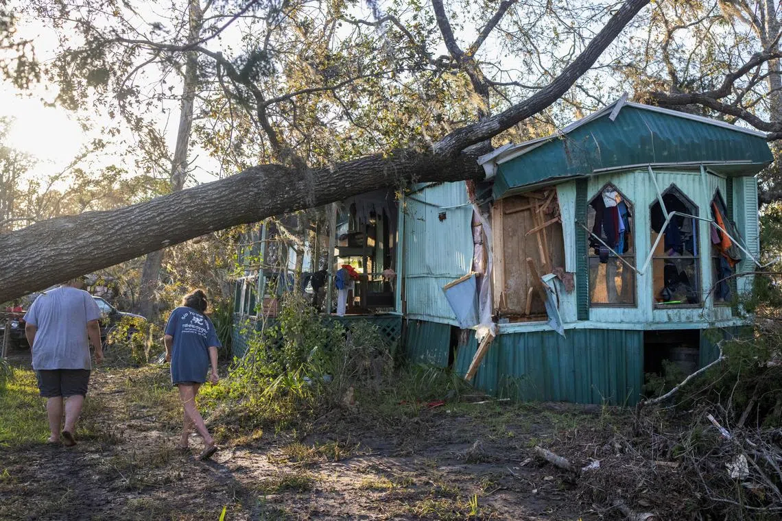 Nash Harris and his mother Alicia walk towards the home where they had been living to try and find some salvageable clothing after Hurricane Helene made landfall in Steinhatchee, Florida, U.S., September 27, 2024. REUTERS/Kathleen Flynn