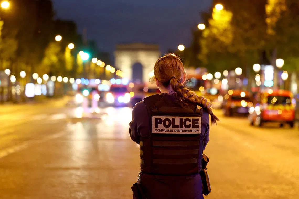 FILE PHOTO: A Police officer stands guard on the Champs Elysees avenue, next to the Arc de Triomphe, in Paris, France, April 26, 2025. REUTERS/Abdul Saboor/File Photo