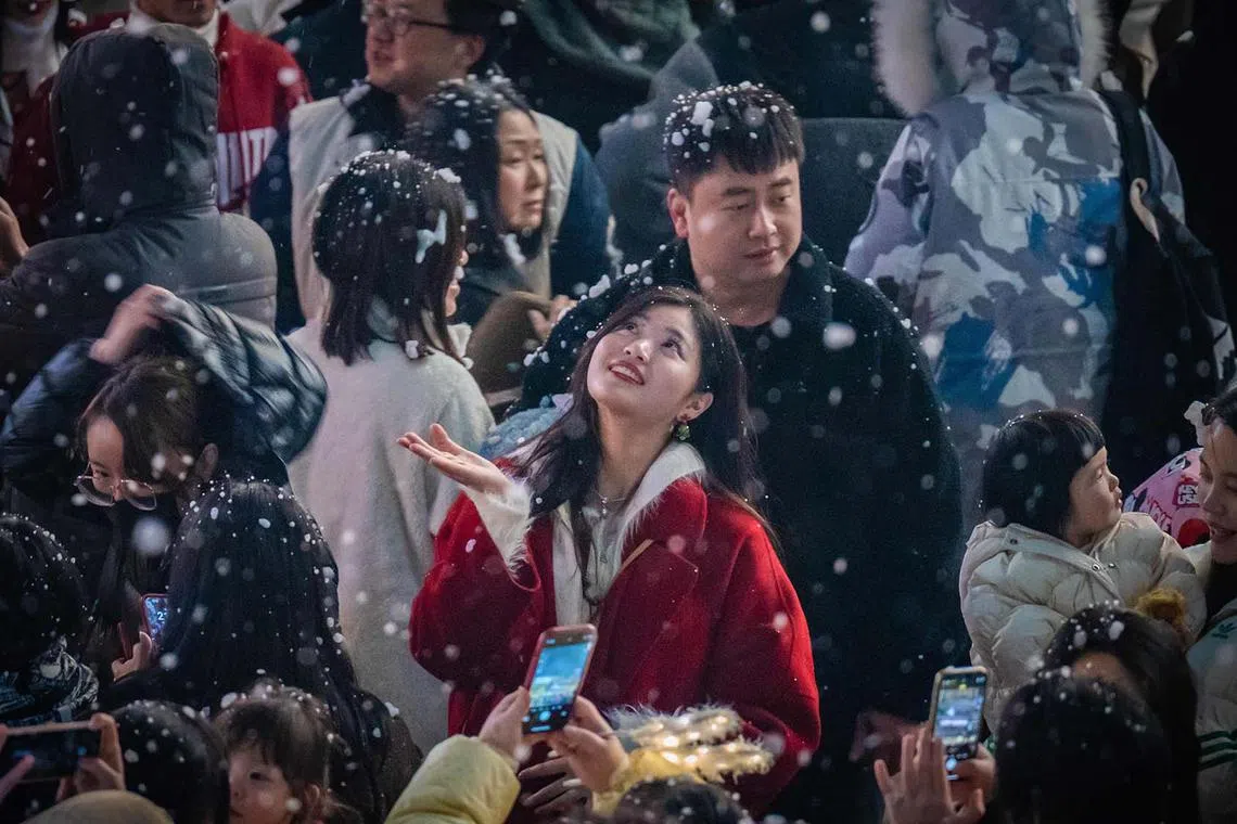 A woman watching artificial snow at a business area in China's southwestern Chongqing municipality on Dec 24, 2023.