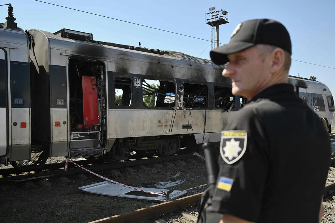 A policeman standing in front of a high-speed train that was heavily damaged during a large-scale Russian drone and missile attack on Kyiv, in August 2025.