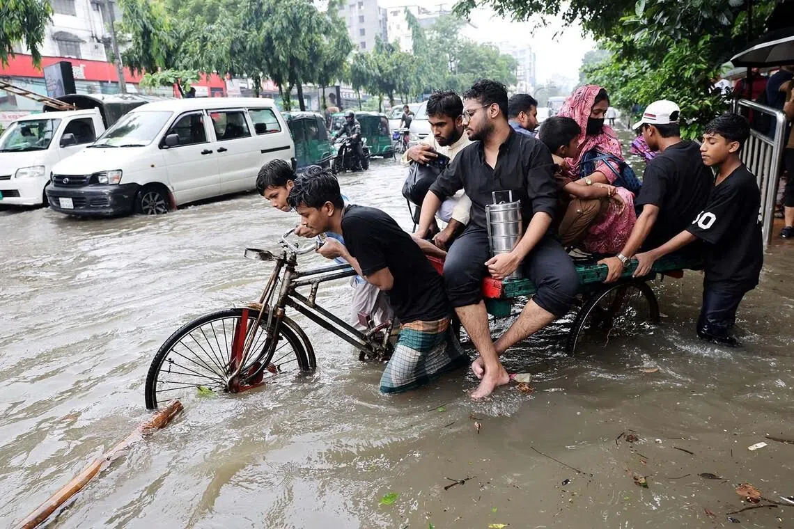 People cross a flooded street on tricycle following torrential rain in Dhaka, Bangladesh, July 12, 2026. REUTERS/Mohammad Ponir Hossain TPX IMAGES OF THE DAY