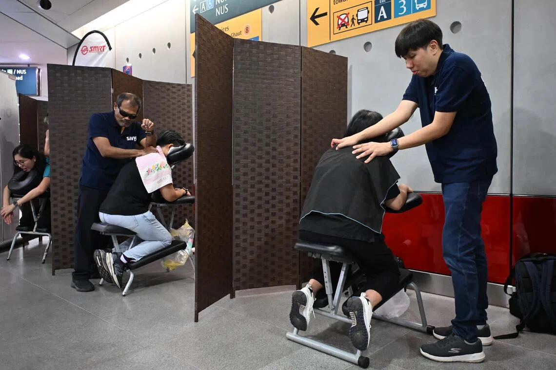 Three reflexologists from the Singapore Association of the Visually Handicapped providing complimentary reflexology to commuters.