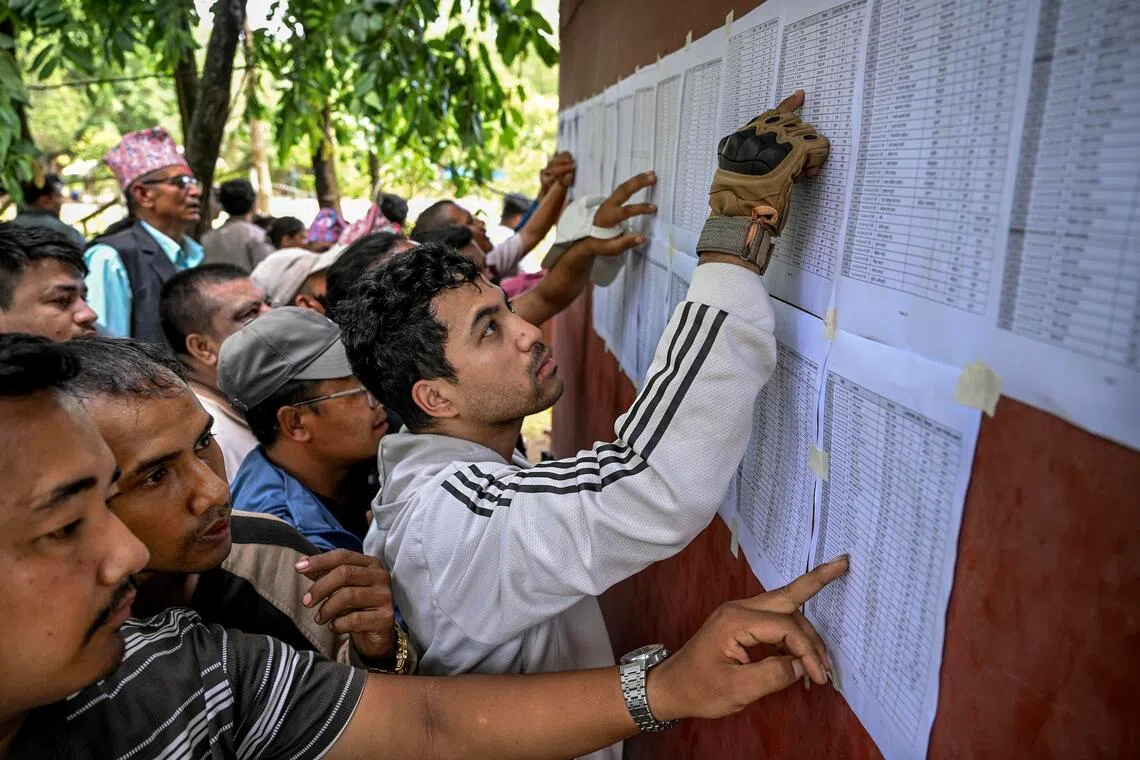 Locals check a list of rescued people published by the Nepali army.