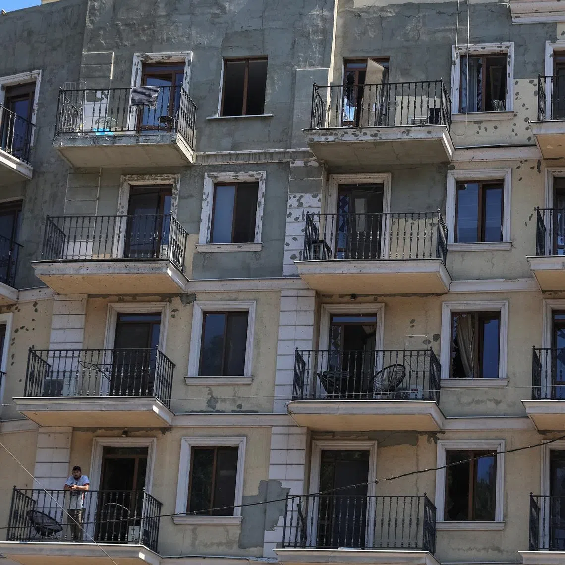 A resident stands on a balcony of an apartment building damaged by a Russian missile strike, amid Russia's attack on Ukraine, in Odesa, Ukraine July 15, 2026. REUTERS/Nina Liashonok