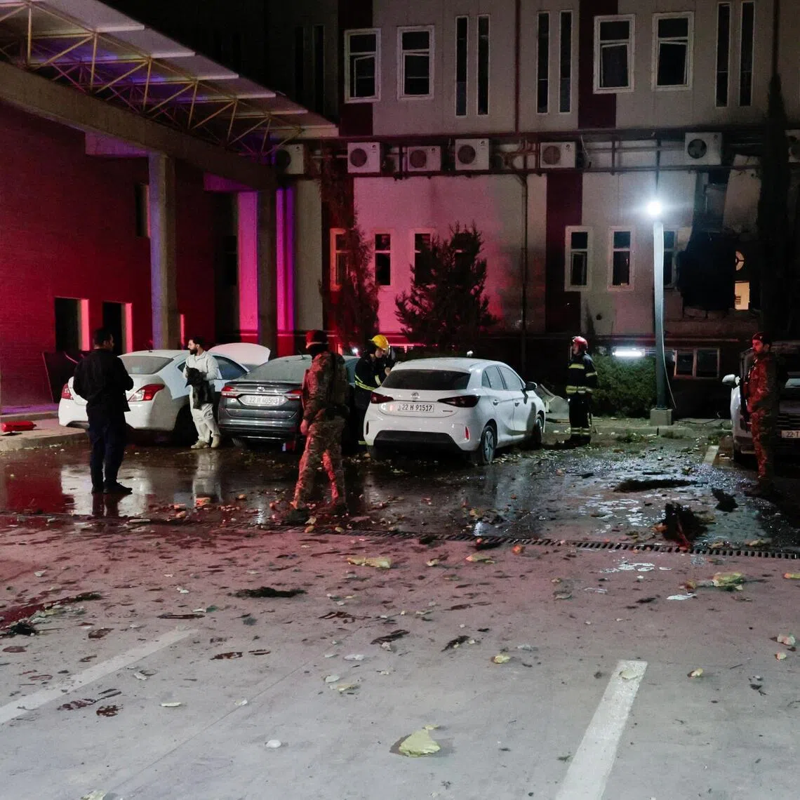 People gather near debris from a drone that fell onto a building near Erbil airport, amid the US-Israeli conflict with Iran, in the Ankawa district of Erbil, Iraq, on March 4, 2026. 
