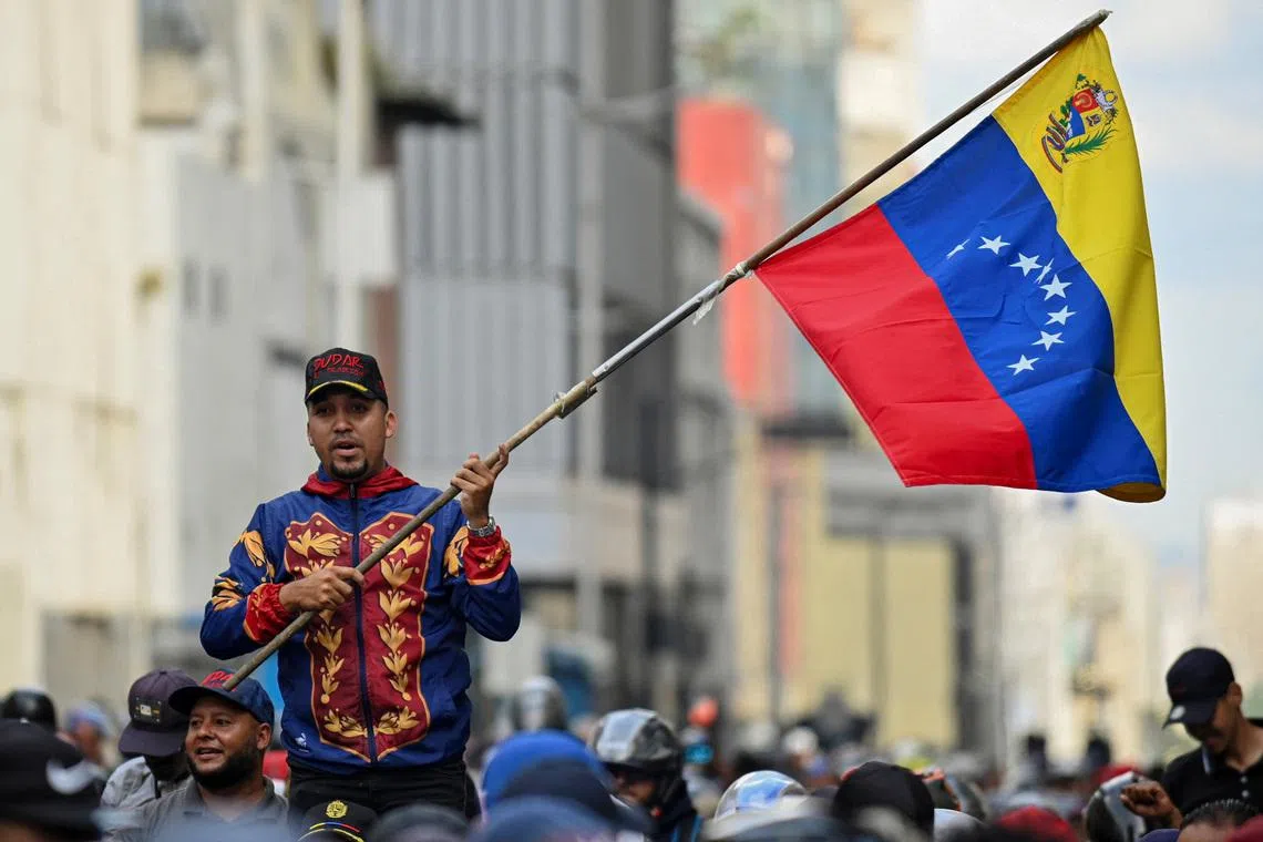 A demonstrator holds a Venezuelan flag during a march outside the National Assembly, in Caracas, Venezuela January 5, 2026. REUTERS/Maxwell Briceno
