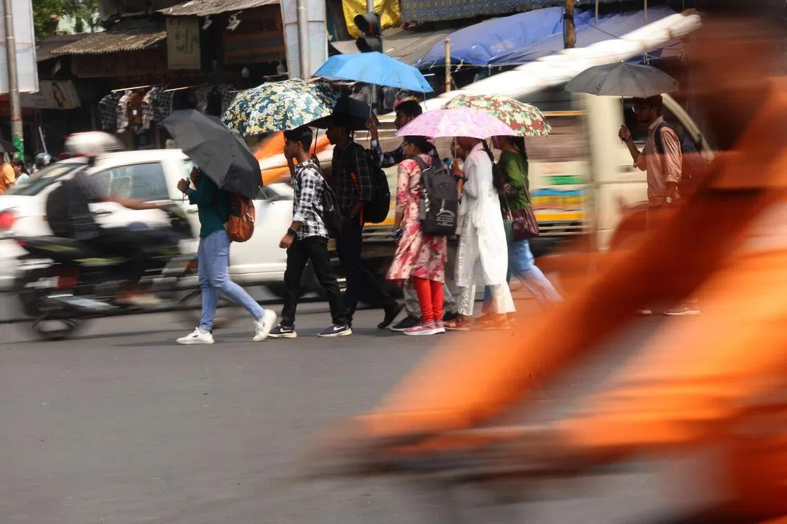 Indian commuters use umbrellas to protect themselves from the sun during a hot afternoon in Kolkata, India, on May 26, 2026. 