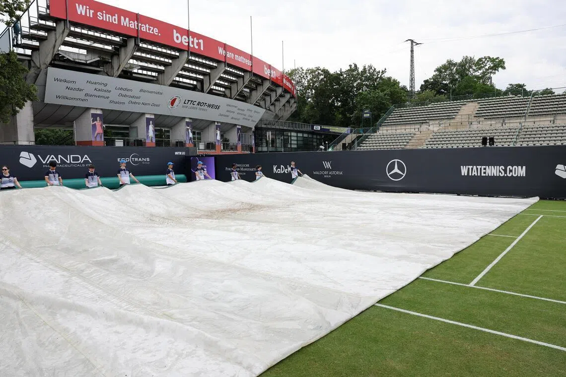 Staff take tarpaulin off of the court at the Steffi Graf Stadium, site of the WTA Berlin Open on June 21, 2026. The final has been suspended due to “severe weather conditions”.