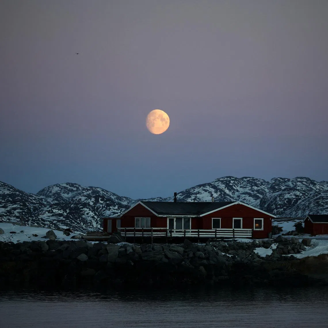The moon rises over a house in Nuuk, Greenland, January 30, 2026. REUTERS/Stoyan Nenov