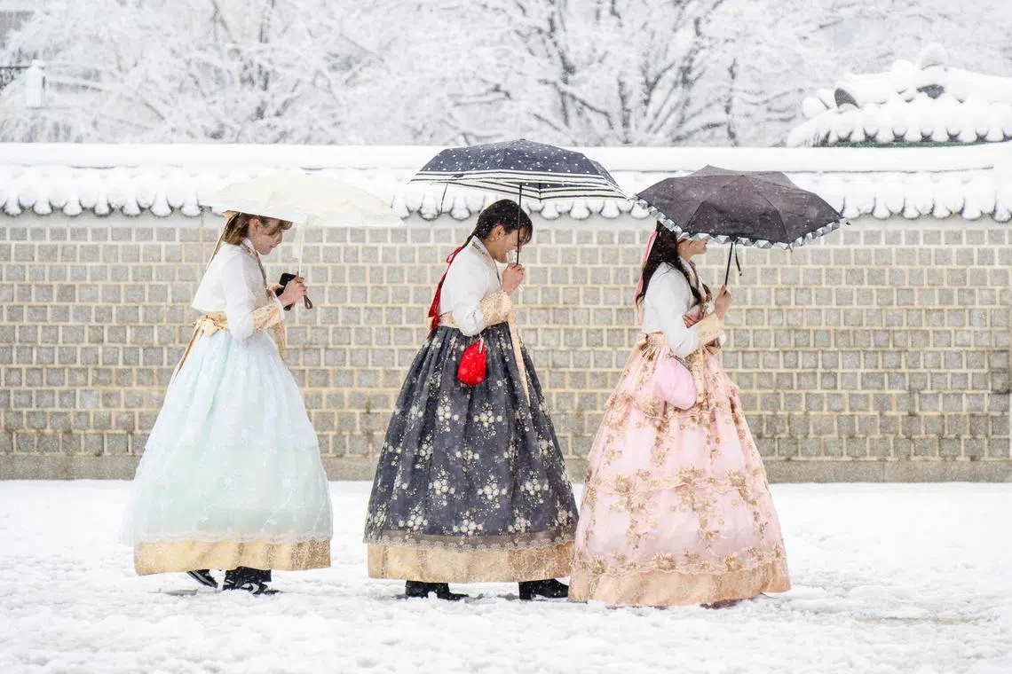 Visitors wearing traditional hanbok dresses are seen on the grounds of Gyeongbokgung Palace amid heavy snowfall in central Seoul, on Nov 27, 2024. 