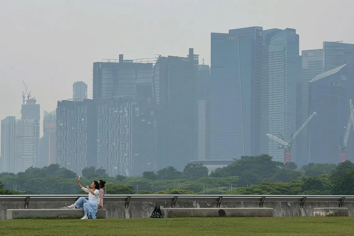 Visitors taking pictures at Marina Barrage, against the hazy backdrop of central business district, at 3.40pm on Oct 20.