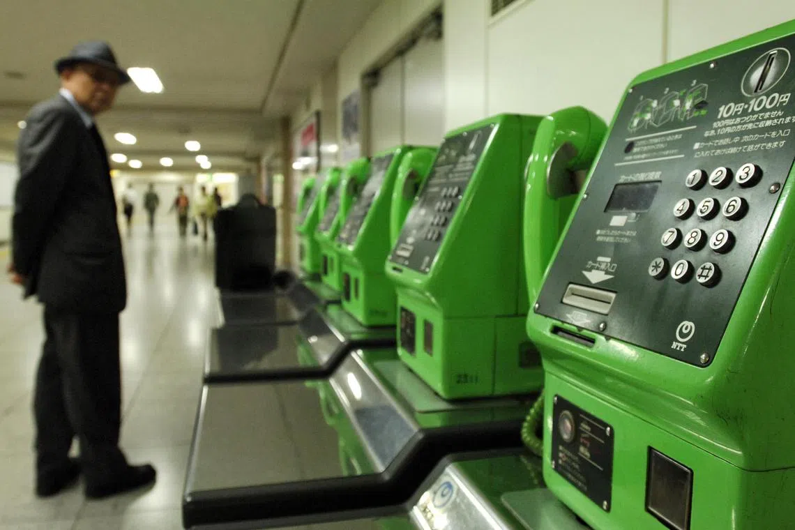 A man waits by a bank of Nippon Telegraph
& Telephone Corp payphones in Tokyo on Tuesday,
September 27, 2005.
