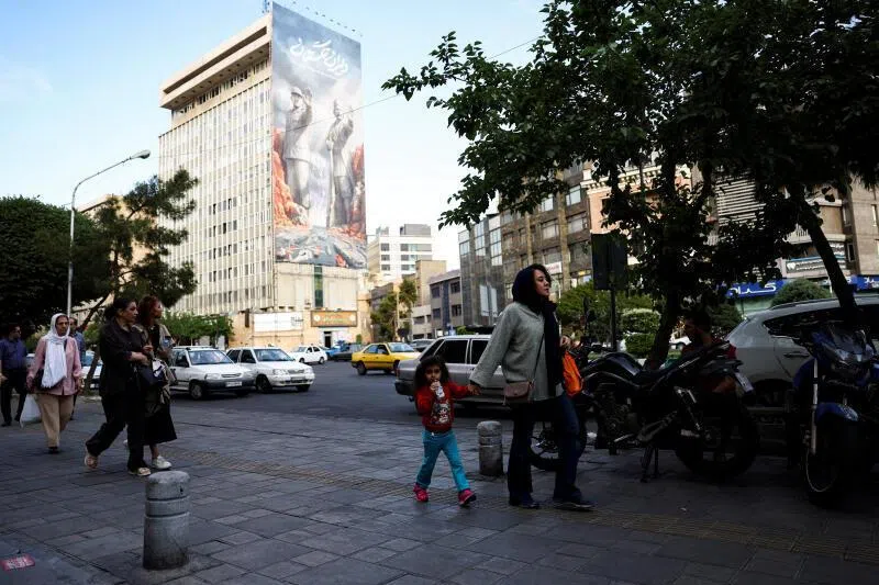 People walking past a billboard about the Strait of Hormuz, in Tehran, Iran, on May 17.