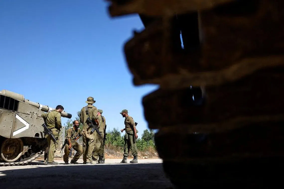 FILE PHOTO: Israeli soldiers gather by military vehicles at Israel's border with Lebanon, in northern Israel, October 25, 2023. REUTERS/Lisi Niesner/File Photo