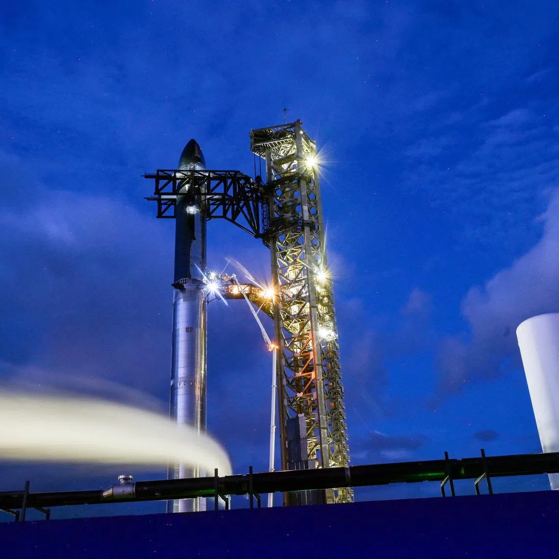 Technicians work from a lift bucket before sunrise as preparations to launch a SpaceX Starship spacecraft continues, at the company's complex in Starbase, Texas, U.S., August 25, 2025. REUTERS/Steve Nesius