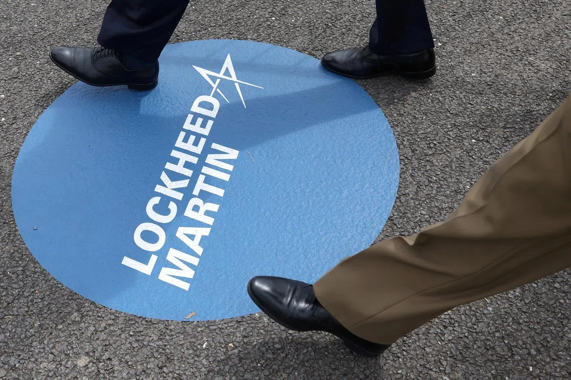 FILE PHOTO: Attendees walk over branding for Lockheed Martin at the Farnborough International Airshow, in Farnborough, Britain, July 22, 2024. REUTERS/Toby Melville/File Photo